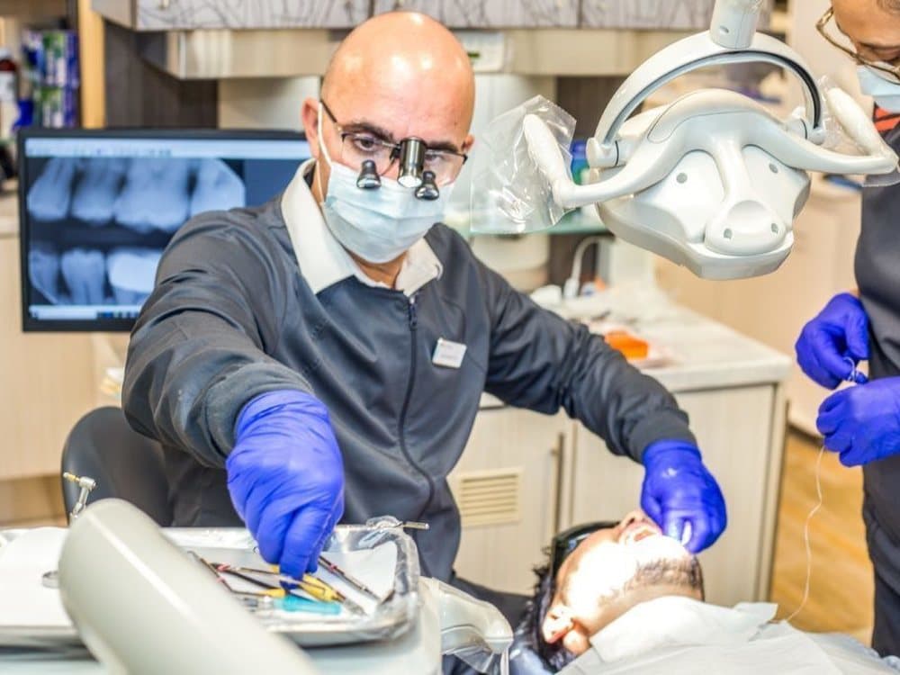 Dr. Garate placing a dental implant with 3D imaging on the monitor behind him